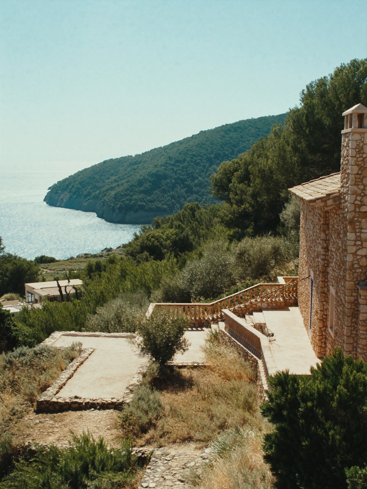 A honey-stone Mallorcan villa with terraces stepping through olive and pine to the sea