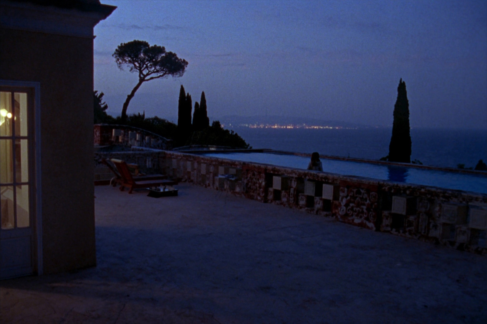 An elegant Mediterranean villa terrace at dusk with an infinity pool reflecting a lilac sky